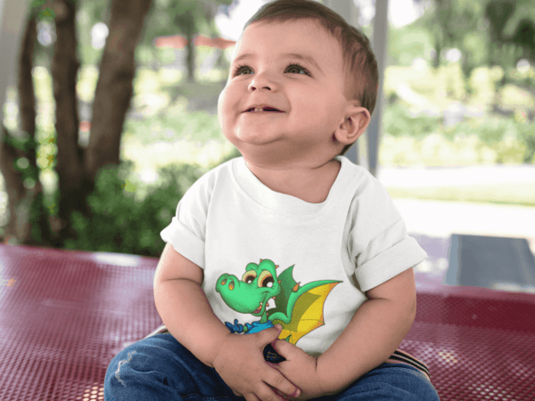 Dinosaur Dragon on Toddler T-Shirt baby boy looking up while smiling wearing a round neck t-shirt mockup