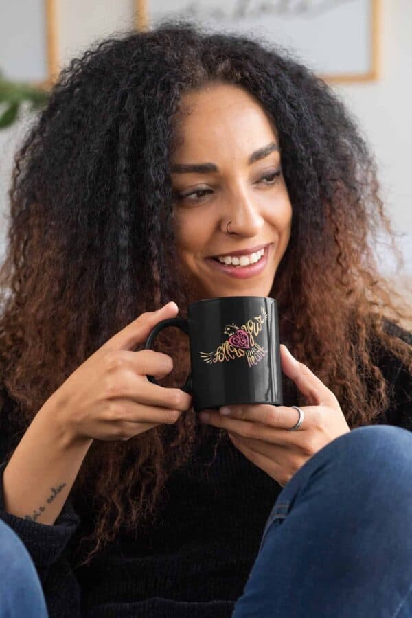 Follow Your Heart Coffee Mug Design mockup of a curly haired woman with an 11oz black mug in her hands