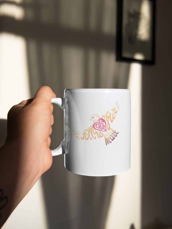 Follow Your Heart Coffee Mug Design on White sticker mockup featuring a man holding a coffee mug