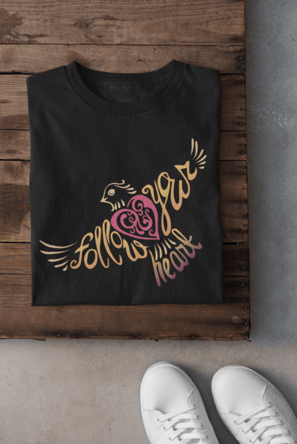 Follow Your Heart T-Shirt Design folded tee mockup against a wooden surface